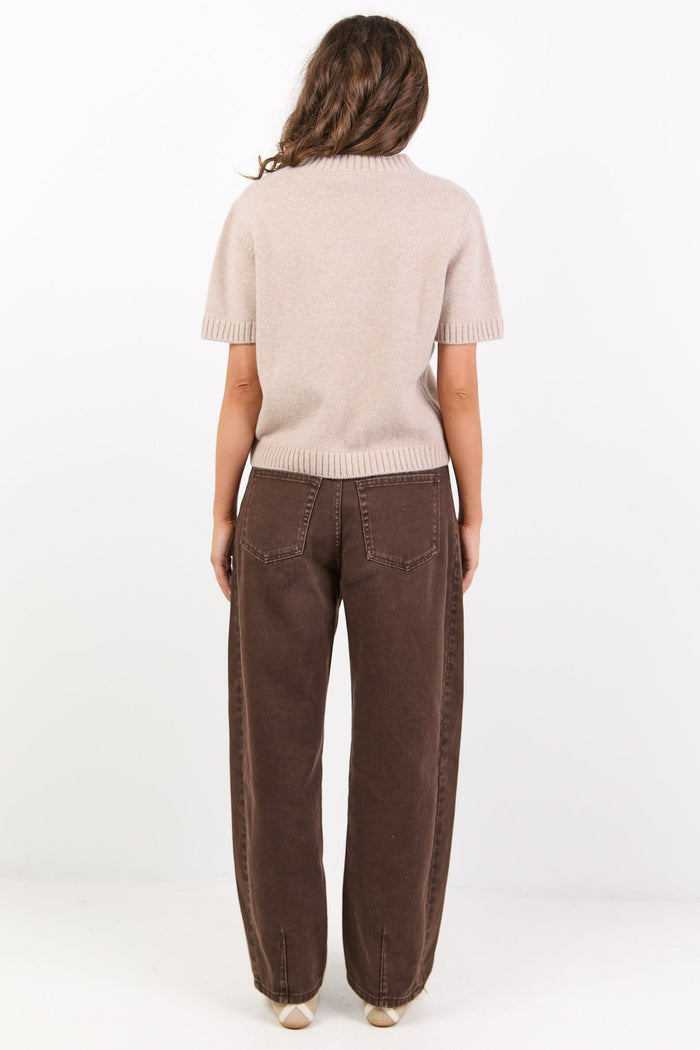 Person wearing a beige sweater and brown pants on a white background