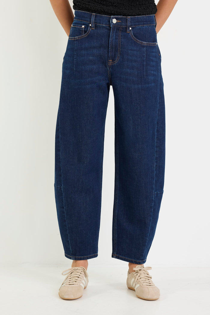 Person wearing blue jeans and a black top on a white background