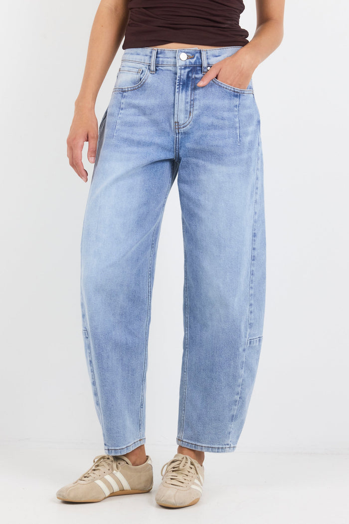 Person wearing light blue jeans and brown shoes on a white background