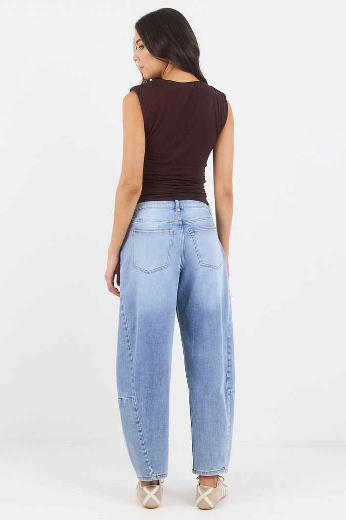Woman wearing light blue jeans and a dark top on a white background