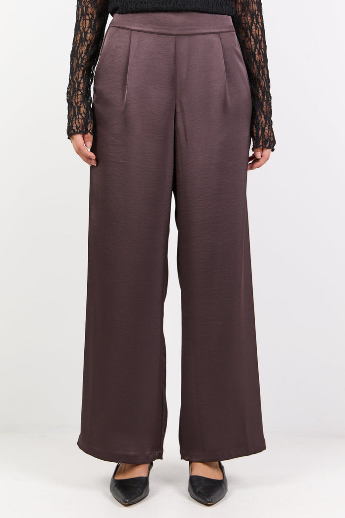 Woman wearing a black top and brown pants on a white background
