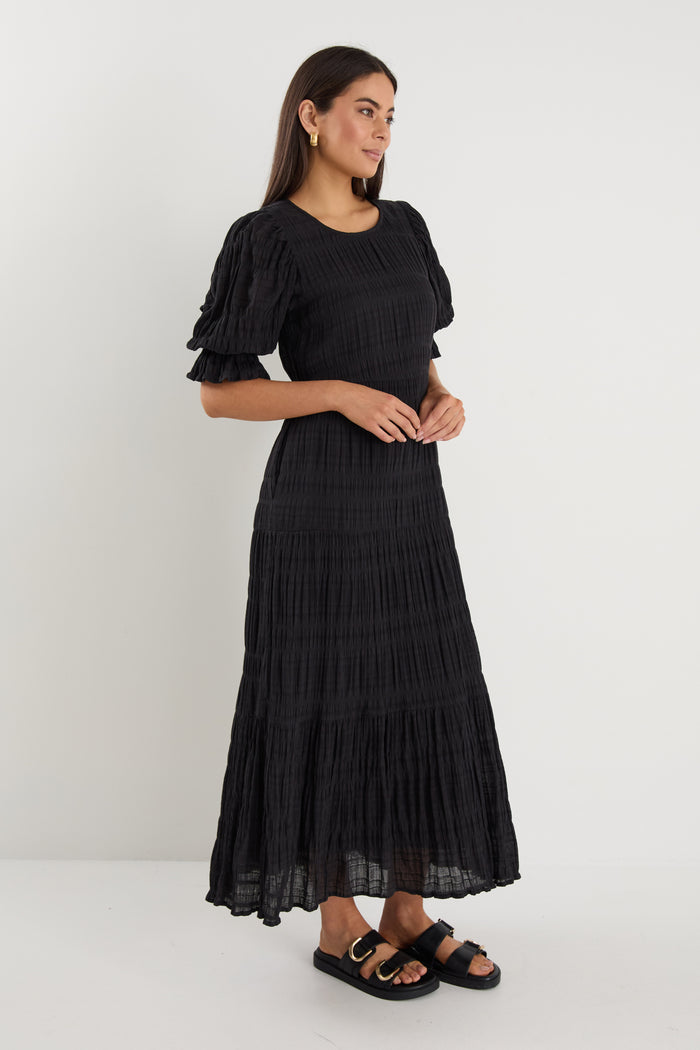 model wears a black maxi dress with black sandals