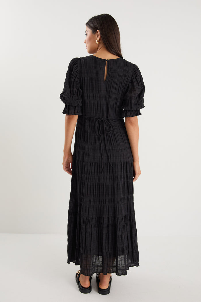 model wears a black maxi dress with black sandals