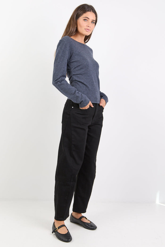 Woman wearing a charcoal top and black pants on a white background