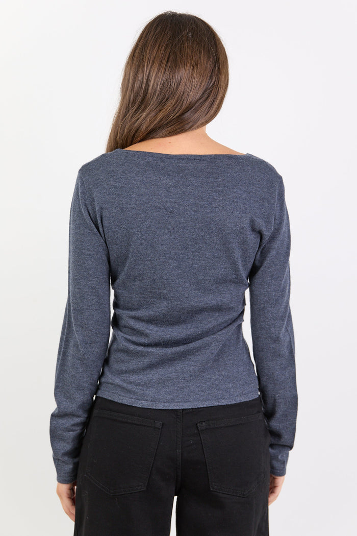 Person wearing a charcoal long-sleeve shirt and black pants on a white background