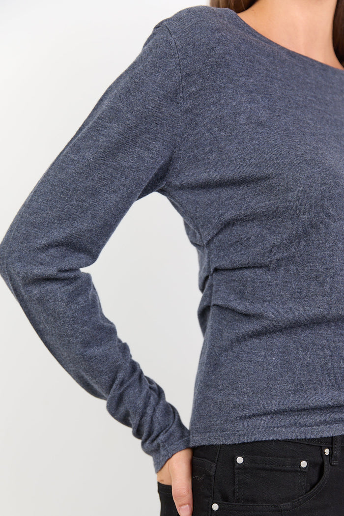 Person wearing a charcoal long-sleeve top and black pants on a white background