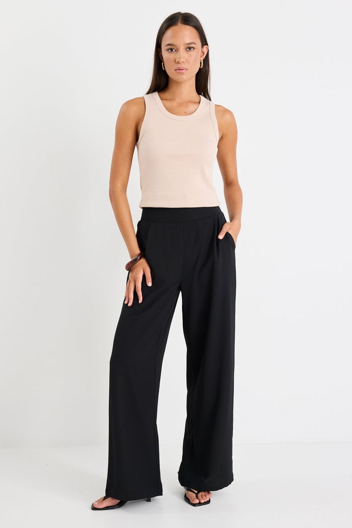 Woman wearing a black pant and beige tank