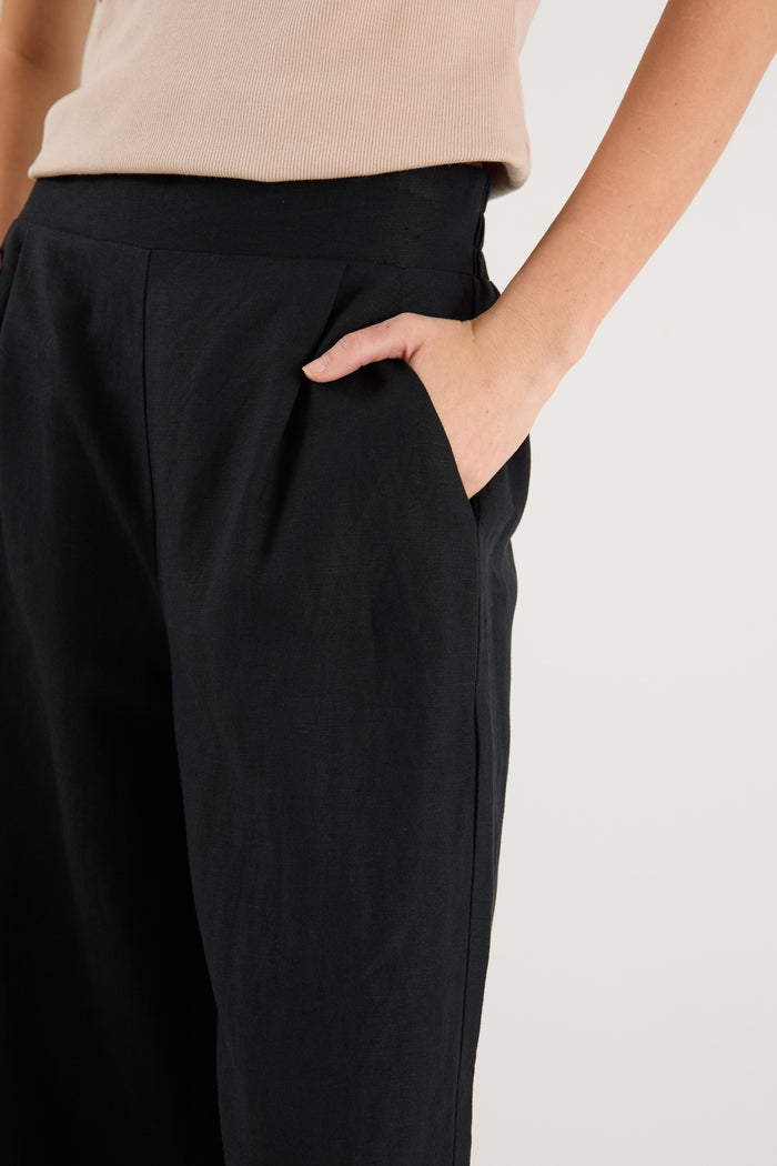 Woman wearing a black pant and beige tank