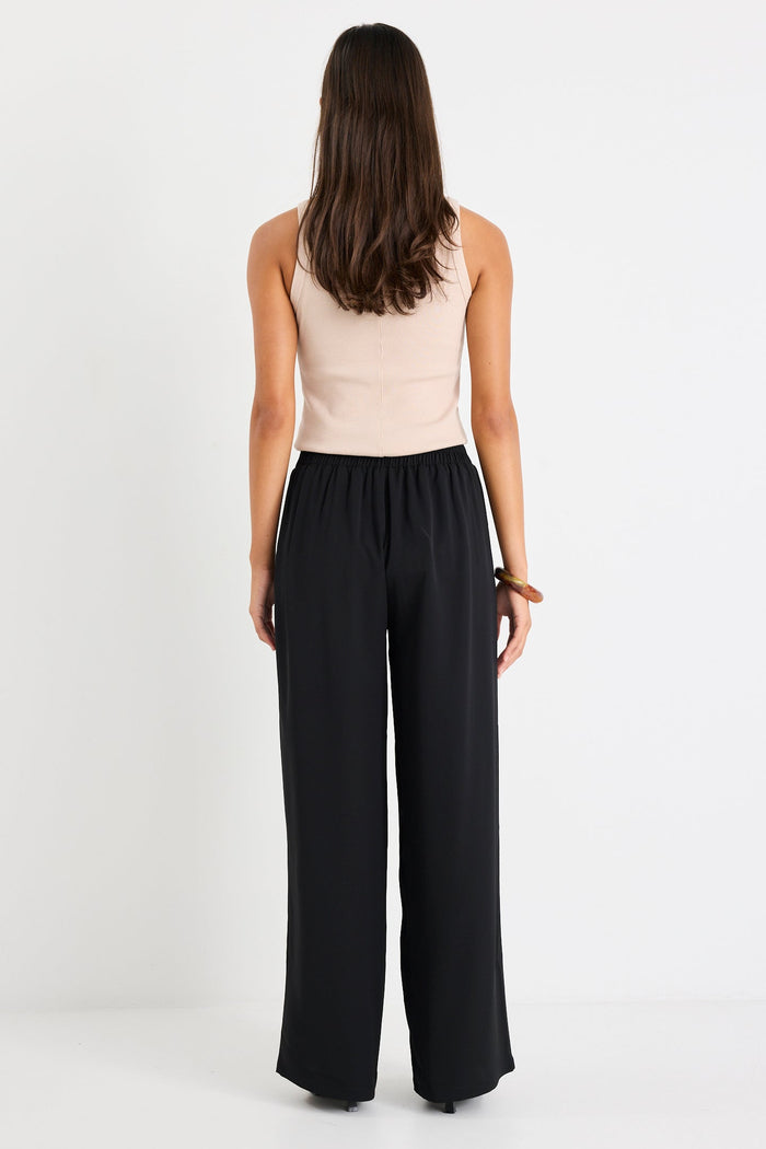 Woman wearing a black pant and beige tank
