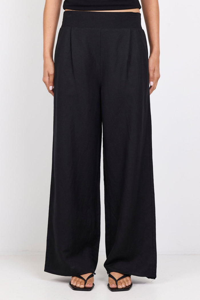 Person wearing black high-waisted pants and a black top on a white background