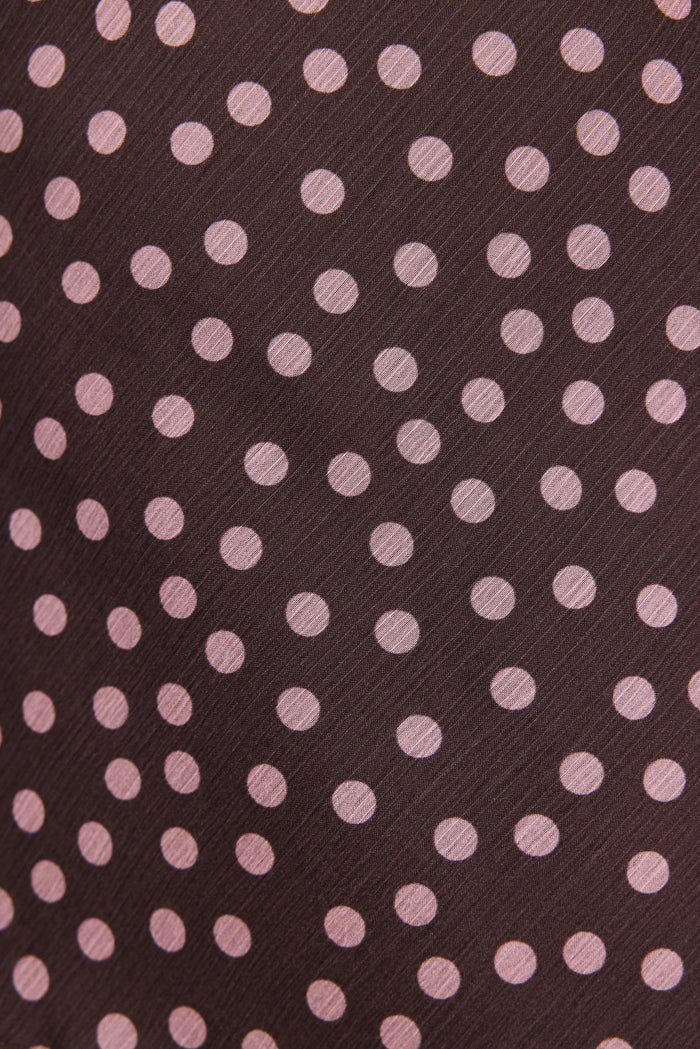 Patterned fabric with pink polka dots on a brown background