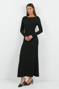 A woman wearing a long-sleeve black textured maxi dress with a fitted silhouette.