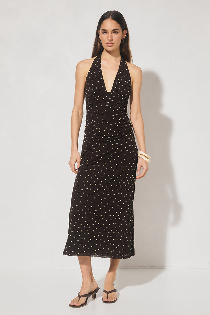 Woman wearing a black dress with white polka dots on a white background