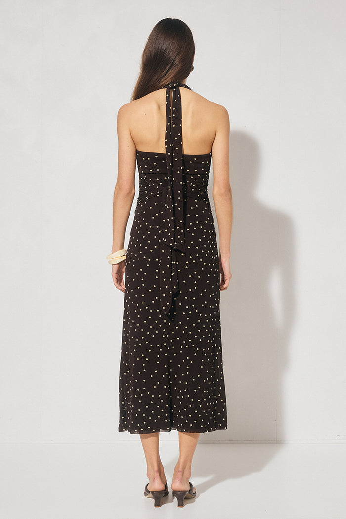 Woman wearing a black dress with white polka dots against a white background