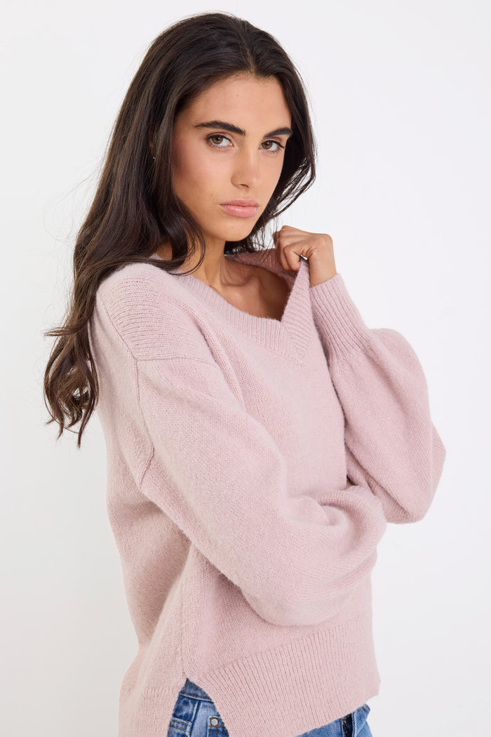 Woman wearing a light pink sweater against a white background