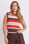 A woman modeling a sleeveless ribbed knit top with horizontal stripes in brown, red, orange, cream, and light pink, paired with brown shorts against a light gray studio background.