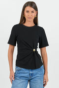 Woman wearing a black top with a gold button and blue jeans on a white background