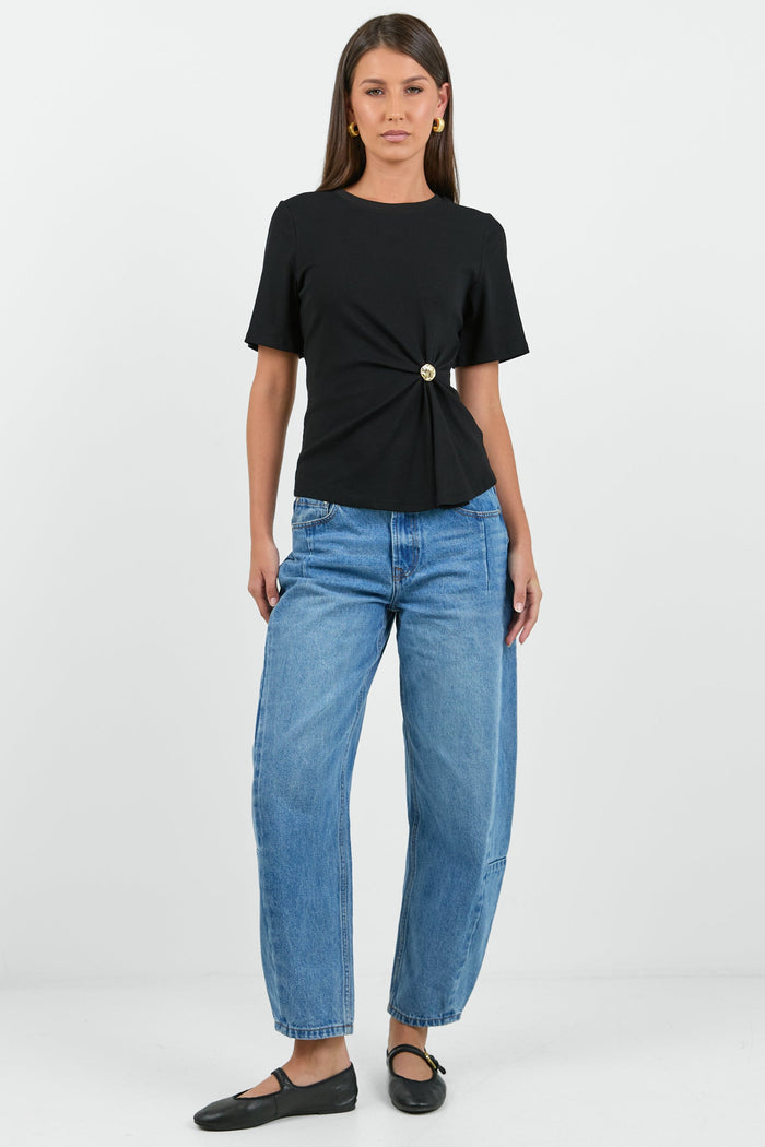 Woman wearing a black top and blue jeans on a white background