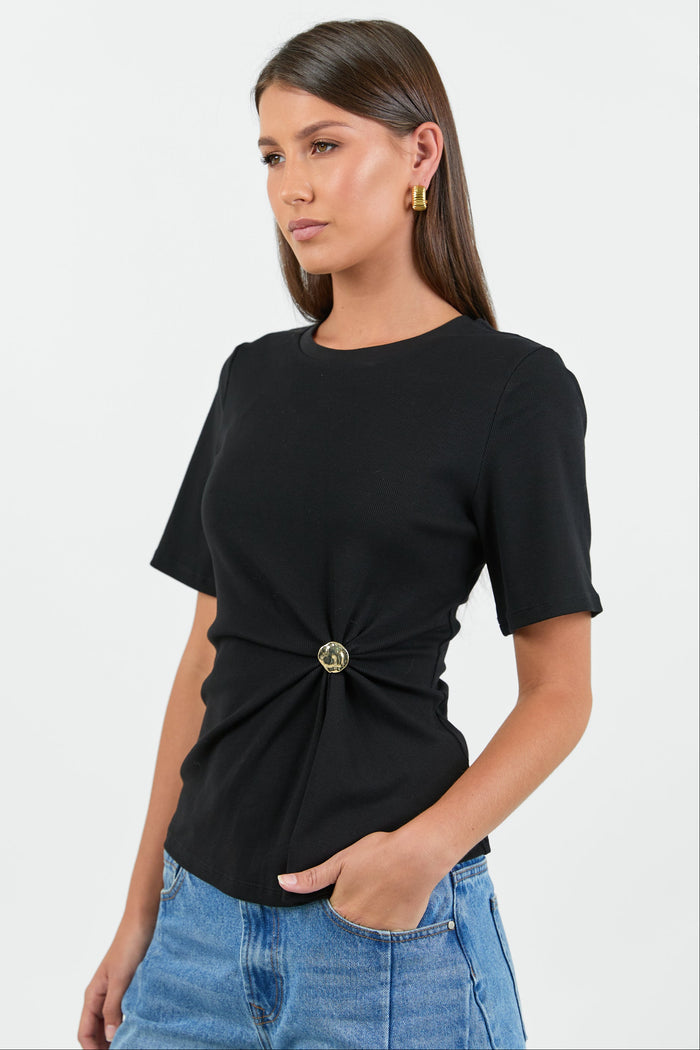 Woman wearing a black t-shirt with a knot detail and blue jeans on a white background