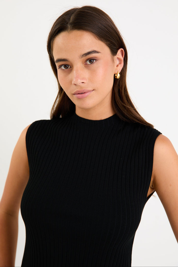 Woman wearing a black sleeveless top against a white background