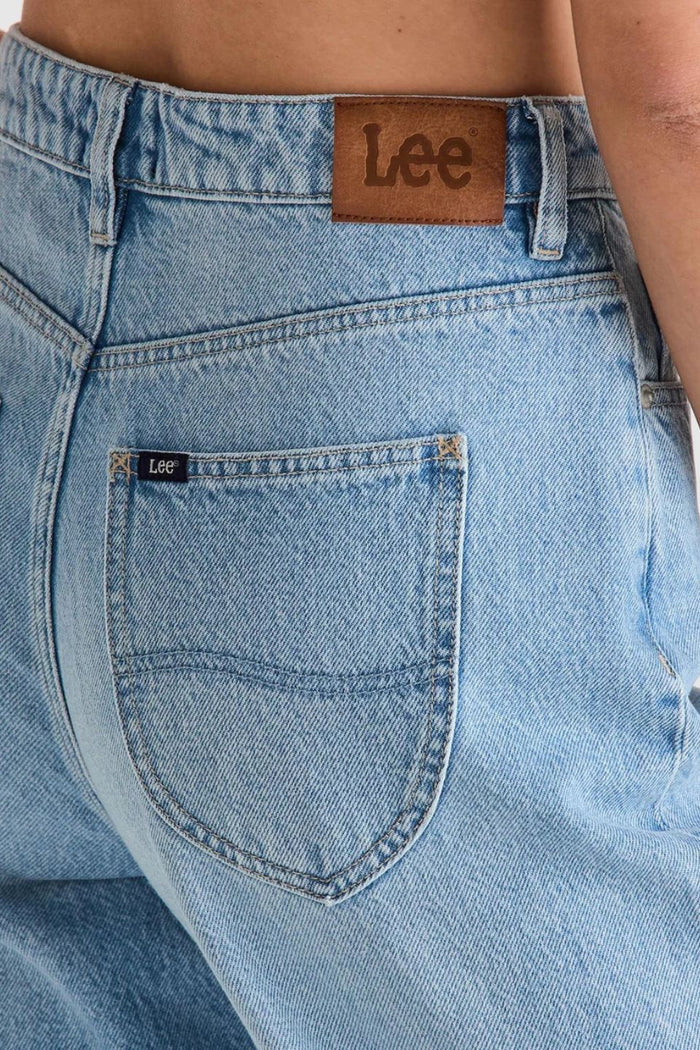 light blue high-rise wide leg jeans with patch pockets and leather logo patch on waistband. Model wears them full length with relaxed fit through the legs.