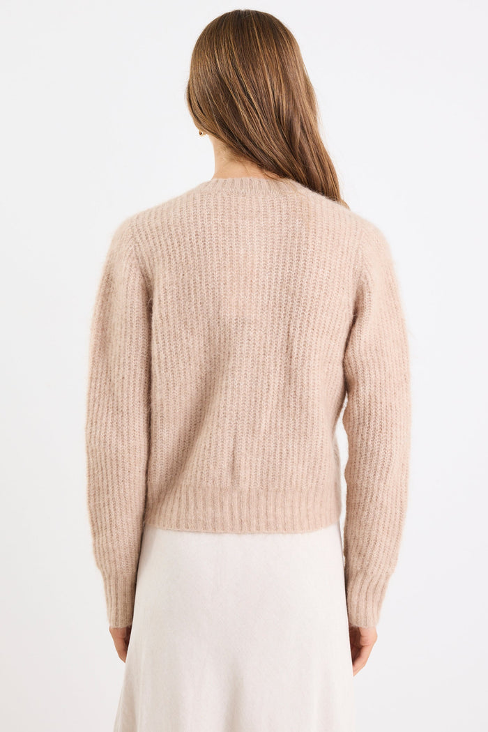 Woman wearing a beige sweater and white pants on a white background
col_pattern