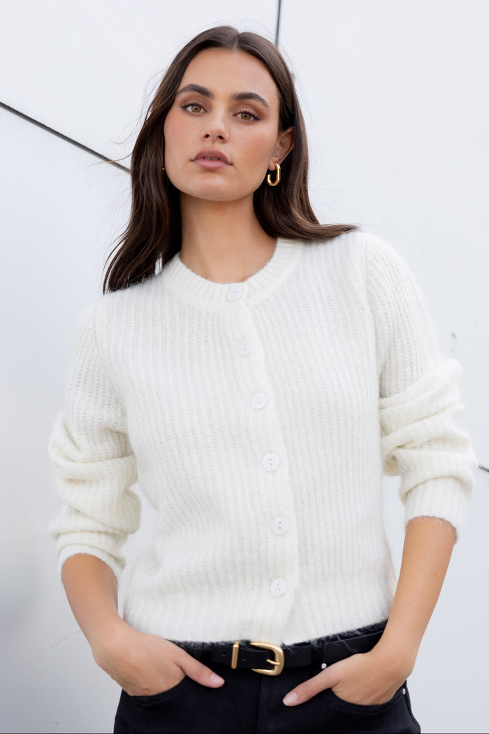Woman wearing a white sweater against a light gray background