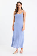 Model wearing a mini gingham strappy slip dress in electric blue, with adjustable straps and a flattering bias cut.