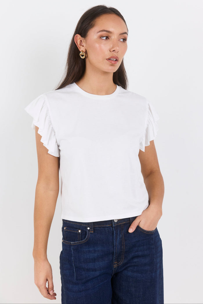 Woman wearing a white ruffled sleeve top and dark blue jeans on a white background