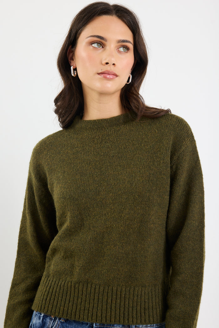 Woman wearing an olive green sweater against a white background