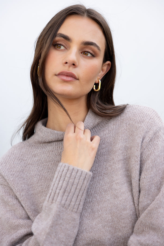 Woman wearing a gray sweater against a white background