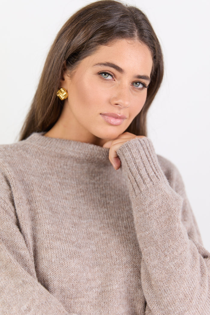 Woman wearing a beige sweater against a white background