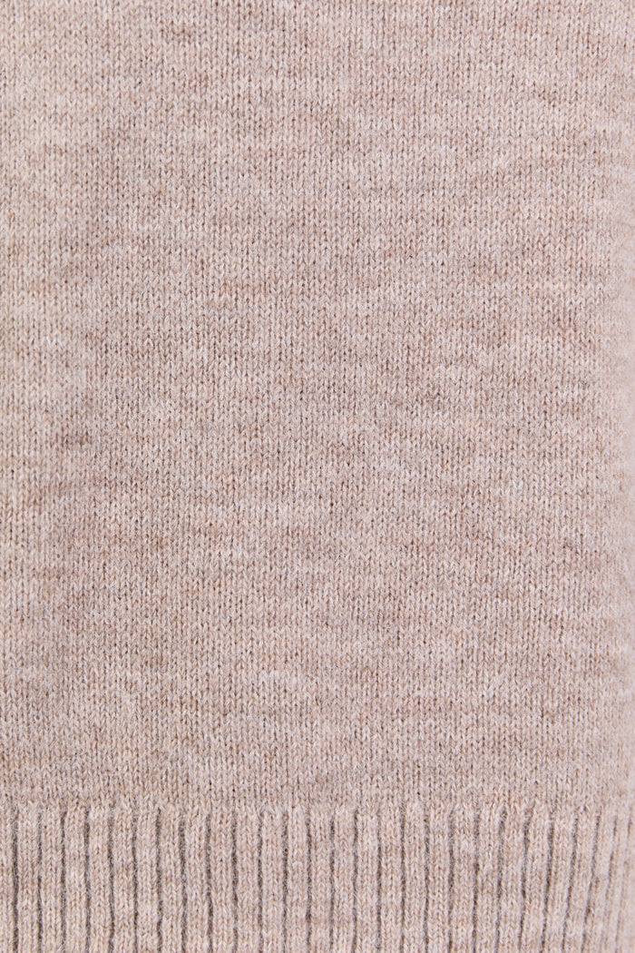 Close-up of a beige knitted fabric with a ribbed edge