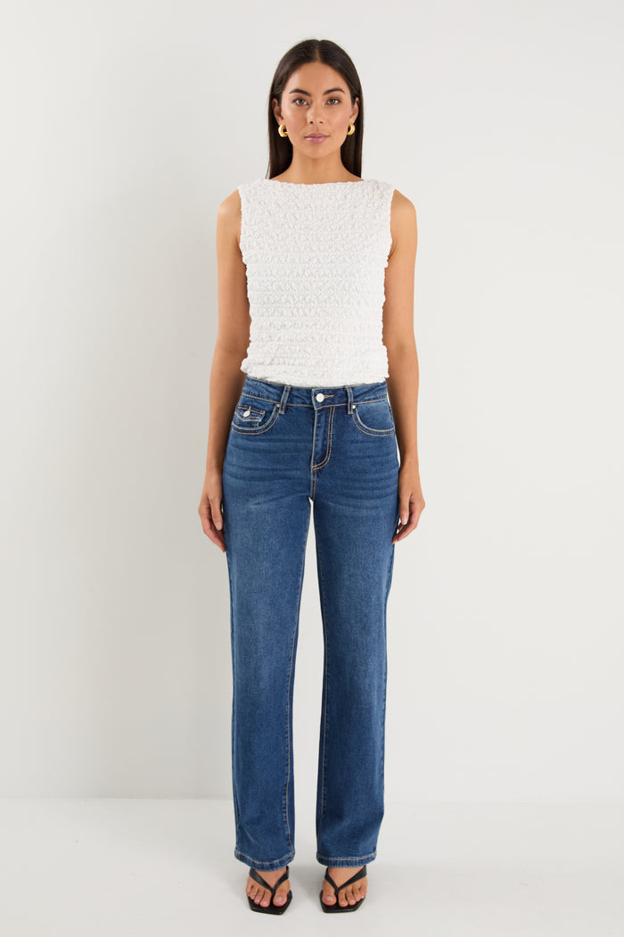 model wears a pair of blue jeans with a white tank top