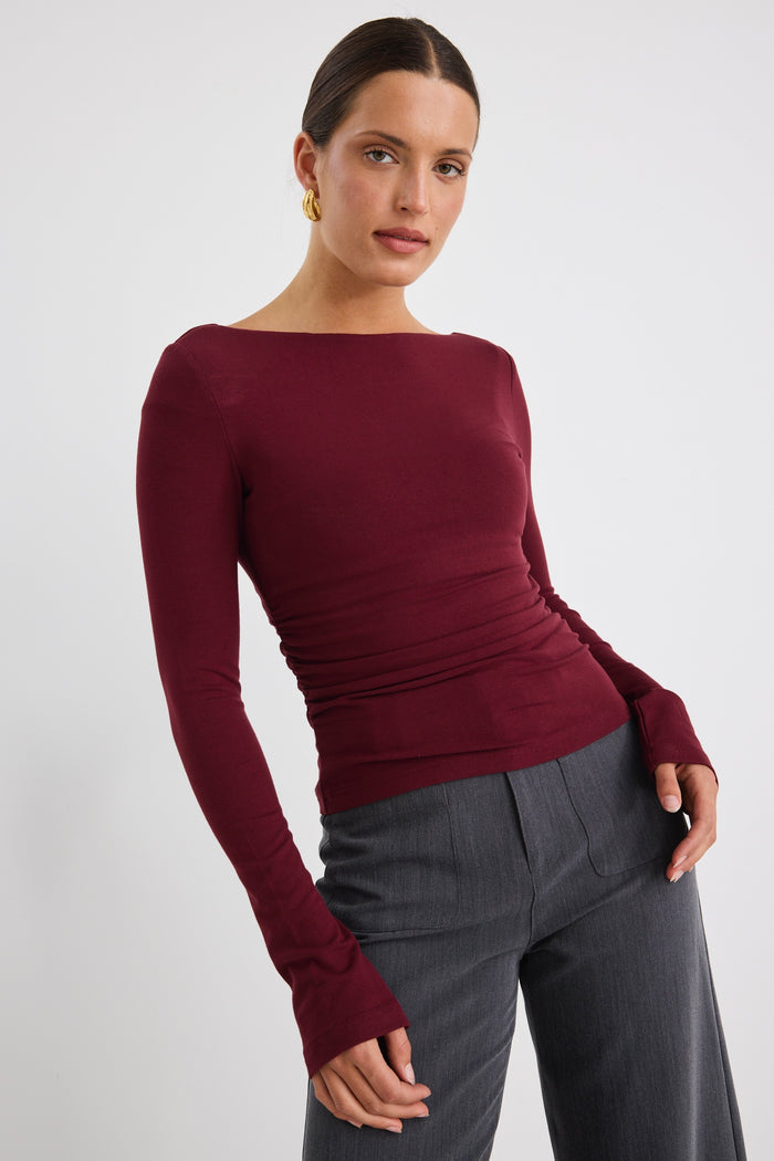 Model wears a burgundy stretch long sleeve top with grey pants.