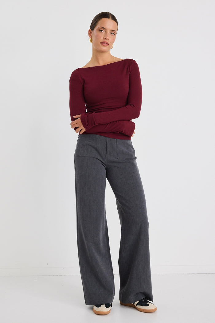 Model wears a burgundy stretch long sleeve top with grey pants.