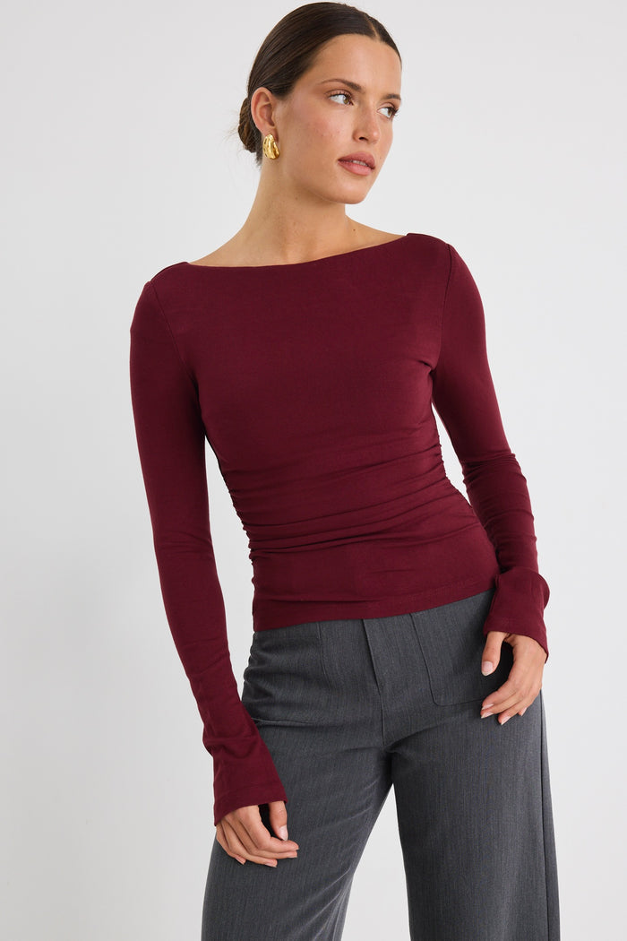 Model wears a burgundy stretch long sleeve top with grey pants.