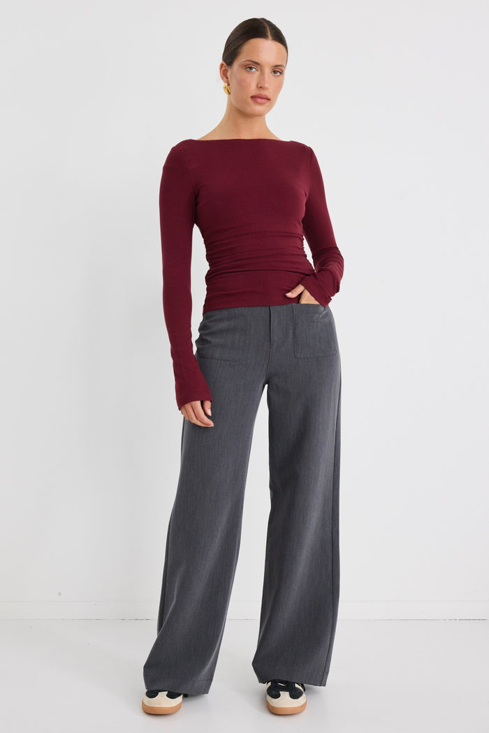 Model wears a burgundy stretch long sleeve top with grey pants.