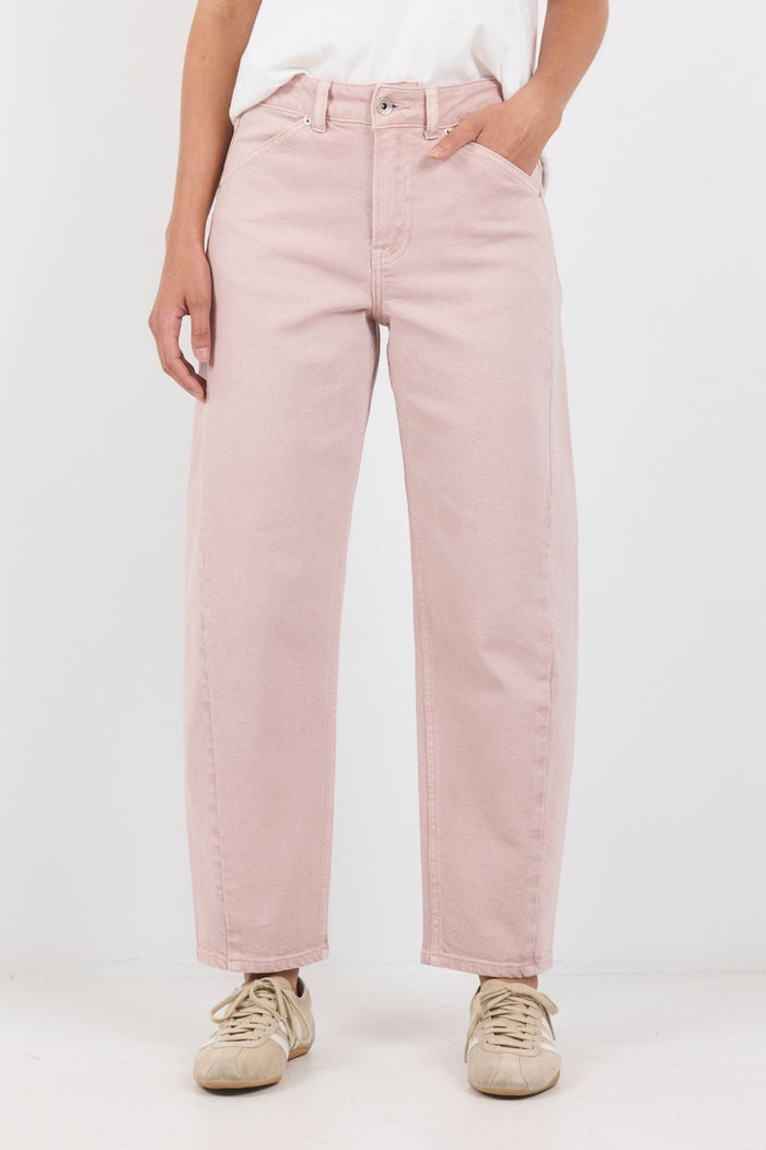 Person wearing light pink jeans and beige sneakers on a white background