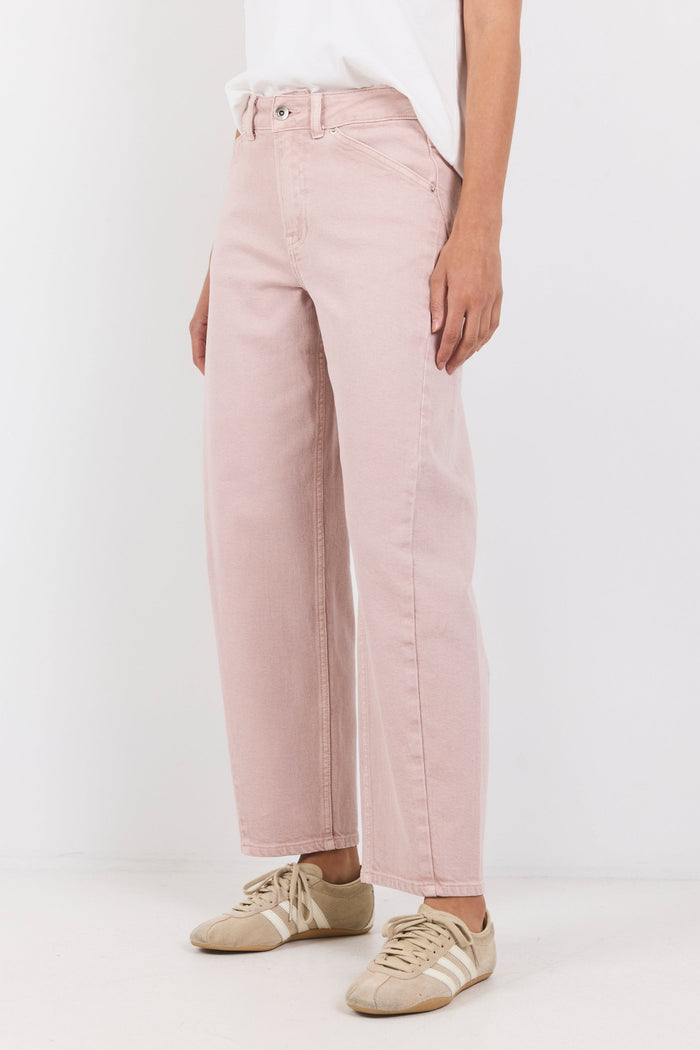Person wearing light pink pants and white sneakers on a white background