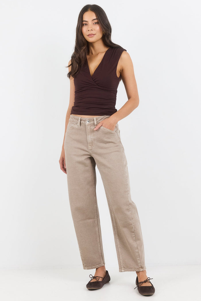 Woman wearing a brown sleeveless top and beige pants on a white background