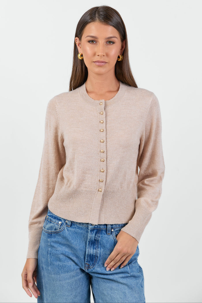 Woman wearing a beige cardigan and blue jeans on a white background