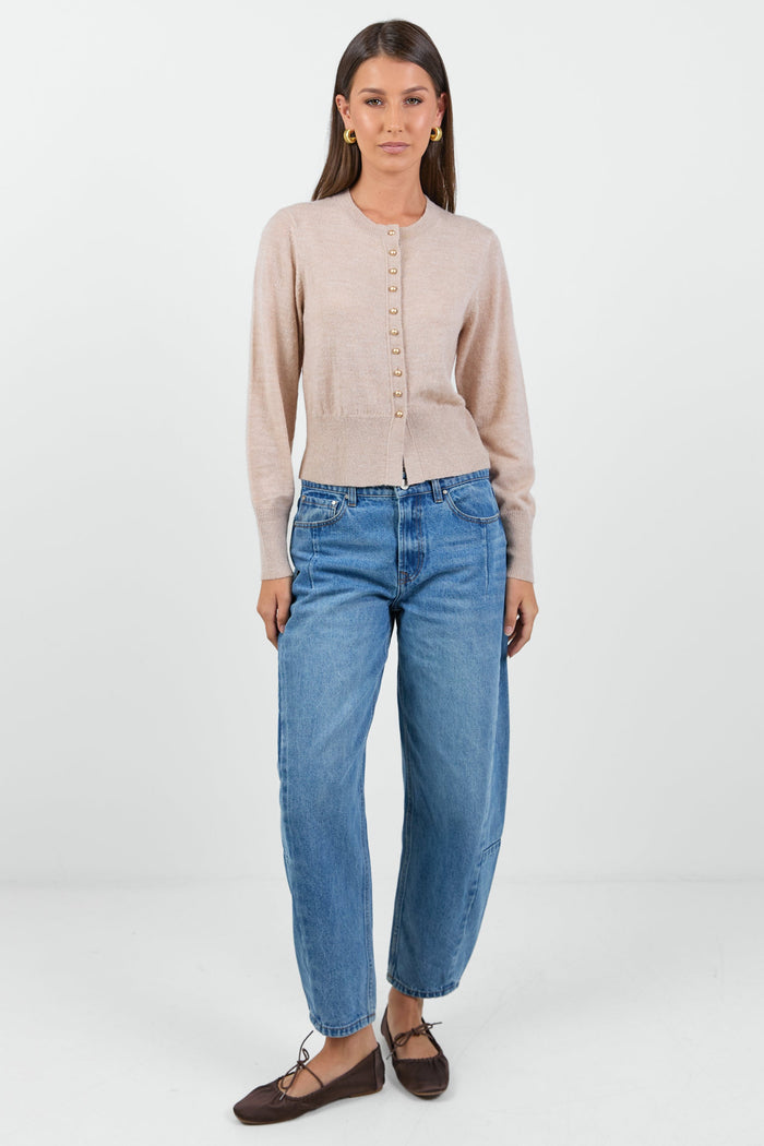 Woman wearing a beige cardigan and blue jeans on a white background