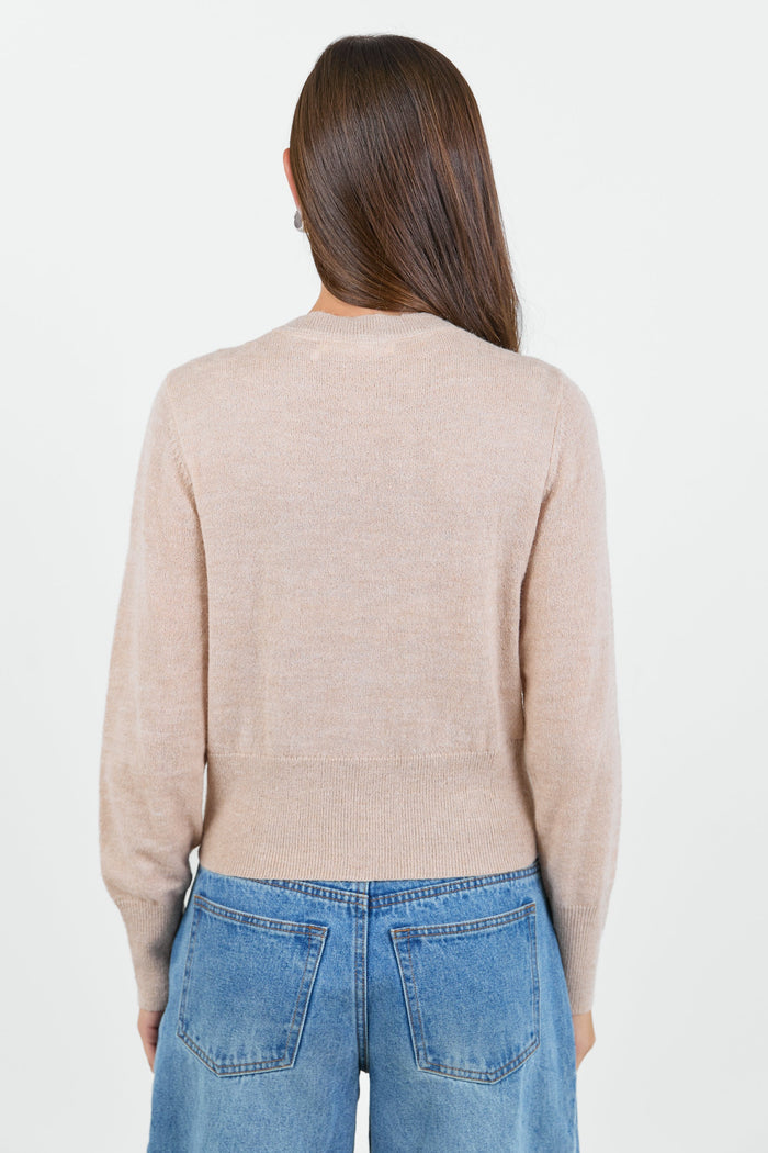 Person wearing a beige sweater and blue jeans on a white background