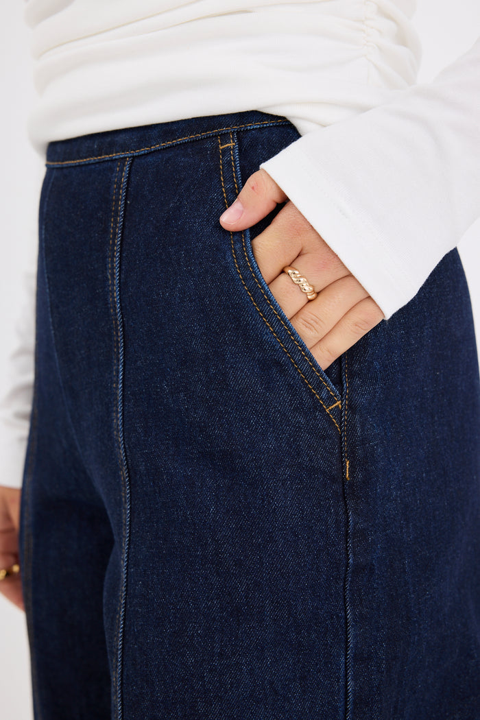 model wears dark blue jeans with a white long sleeve top