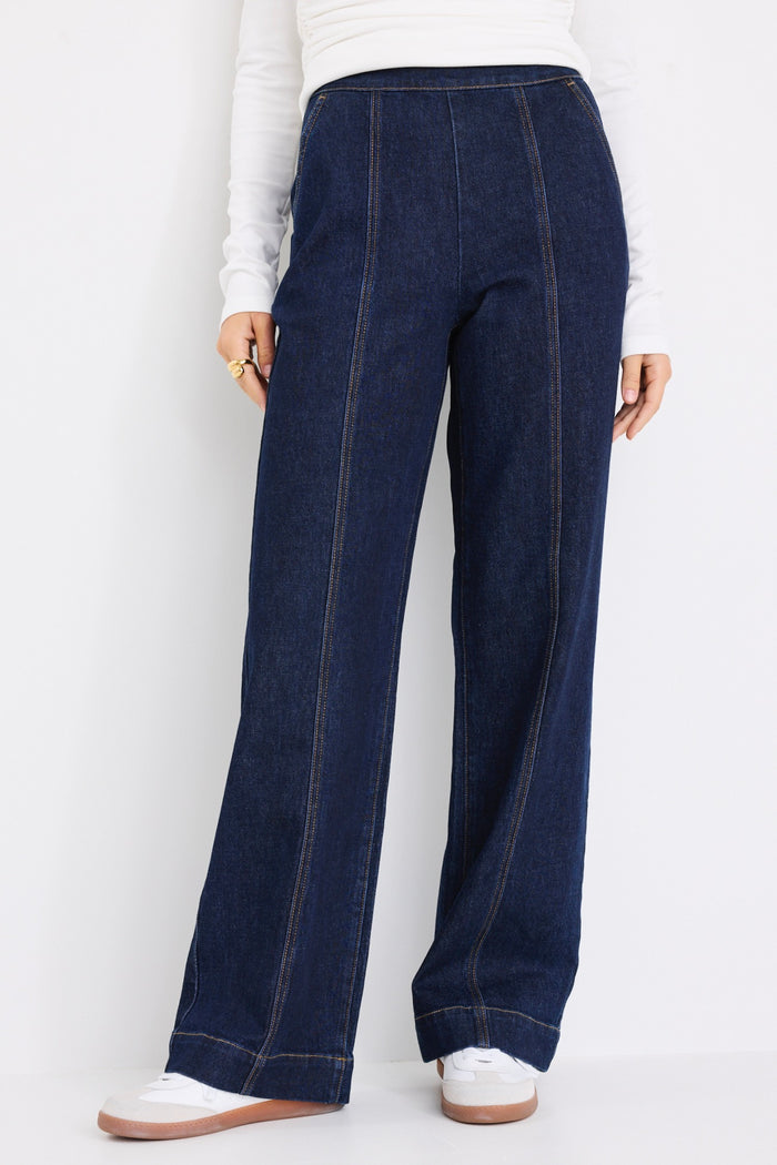 model wears dark blue jeans with a white long sleeve top