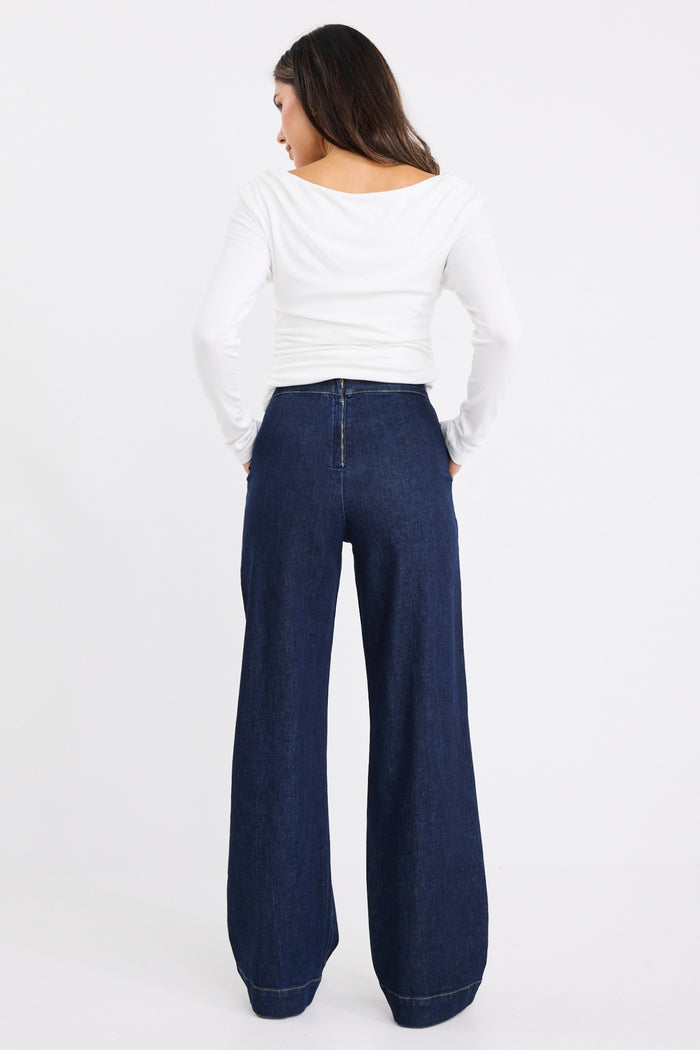 model wears dark blue jeans with a white long sleeve top