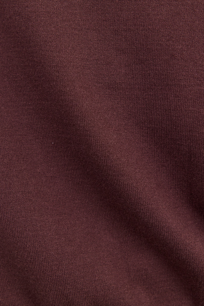A close-up of a dark plum or burgundy knit fabric texture with soft folds.