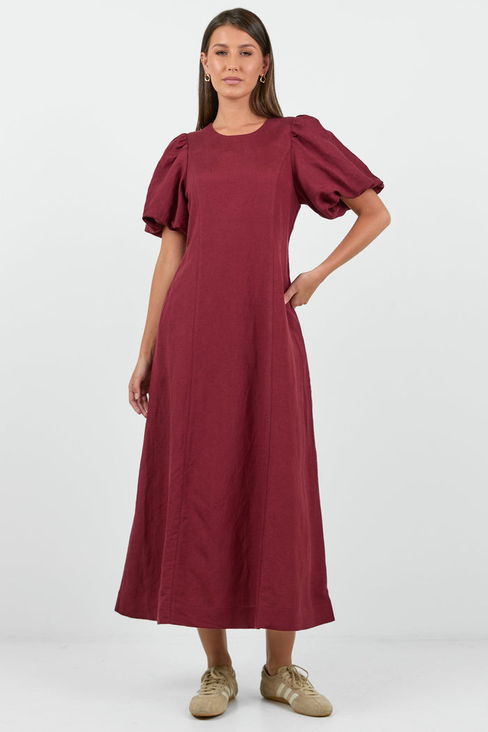 Woman wearing a burgundy dress with puff sleeves on a white background