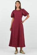 Woman wearing a burgundy dress with puff sleeves on a white background